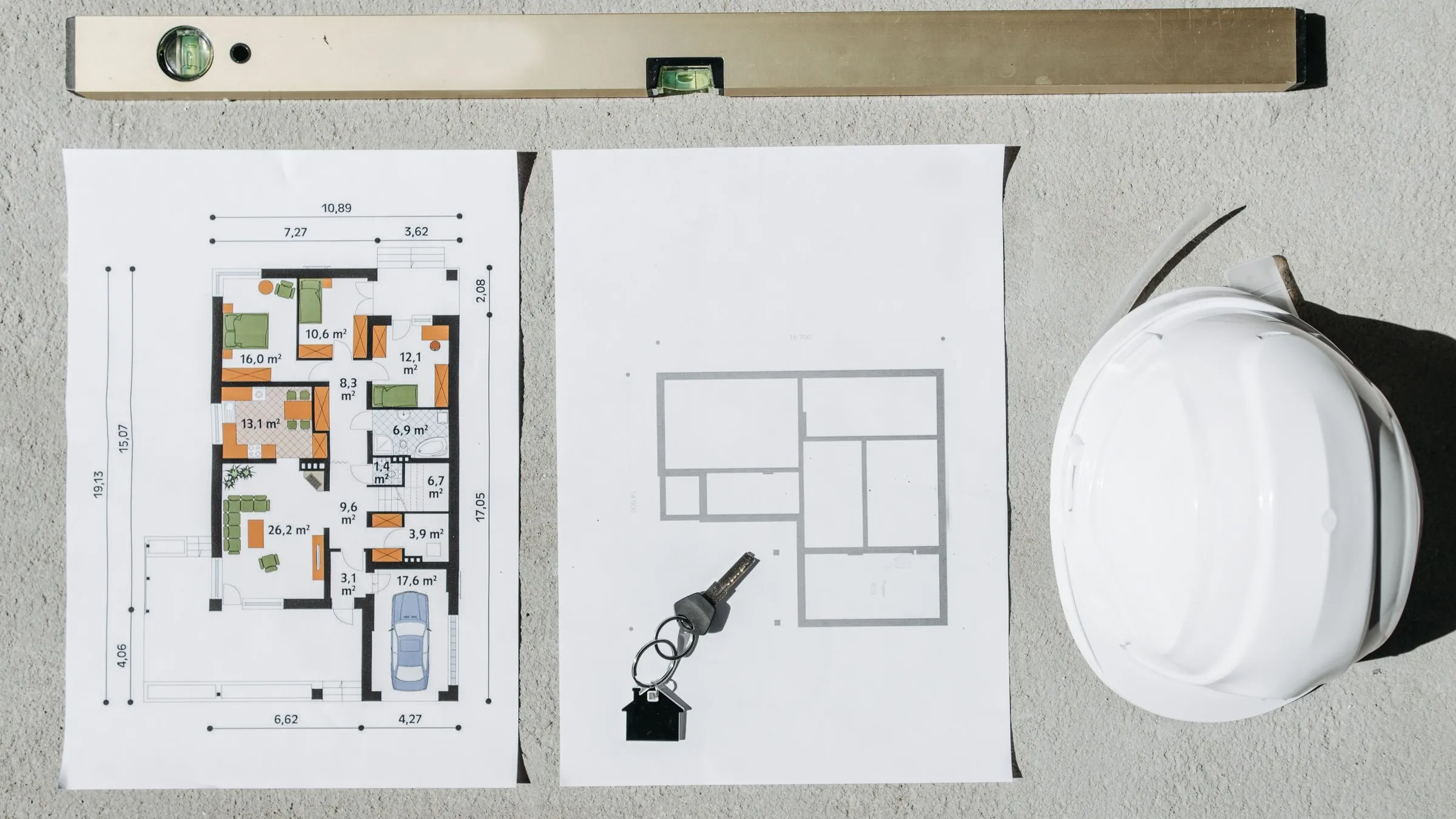 Construction drawings, a tape measure and a calculator laid out on a pale desk